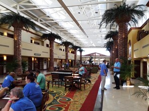 A spacious indoor area with high ceilings, palm trees, and a central walkway. - St Pete Beach | Couples Gulf Coast Retreat | Pool + Beach (St. Pete Beach)