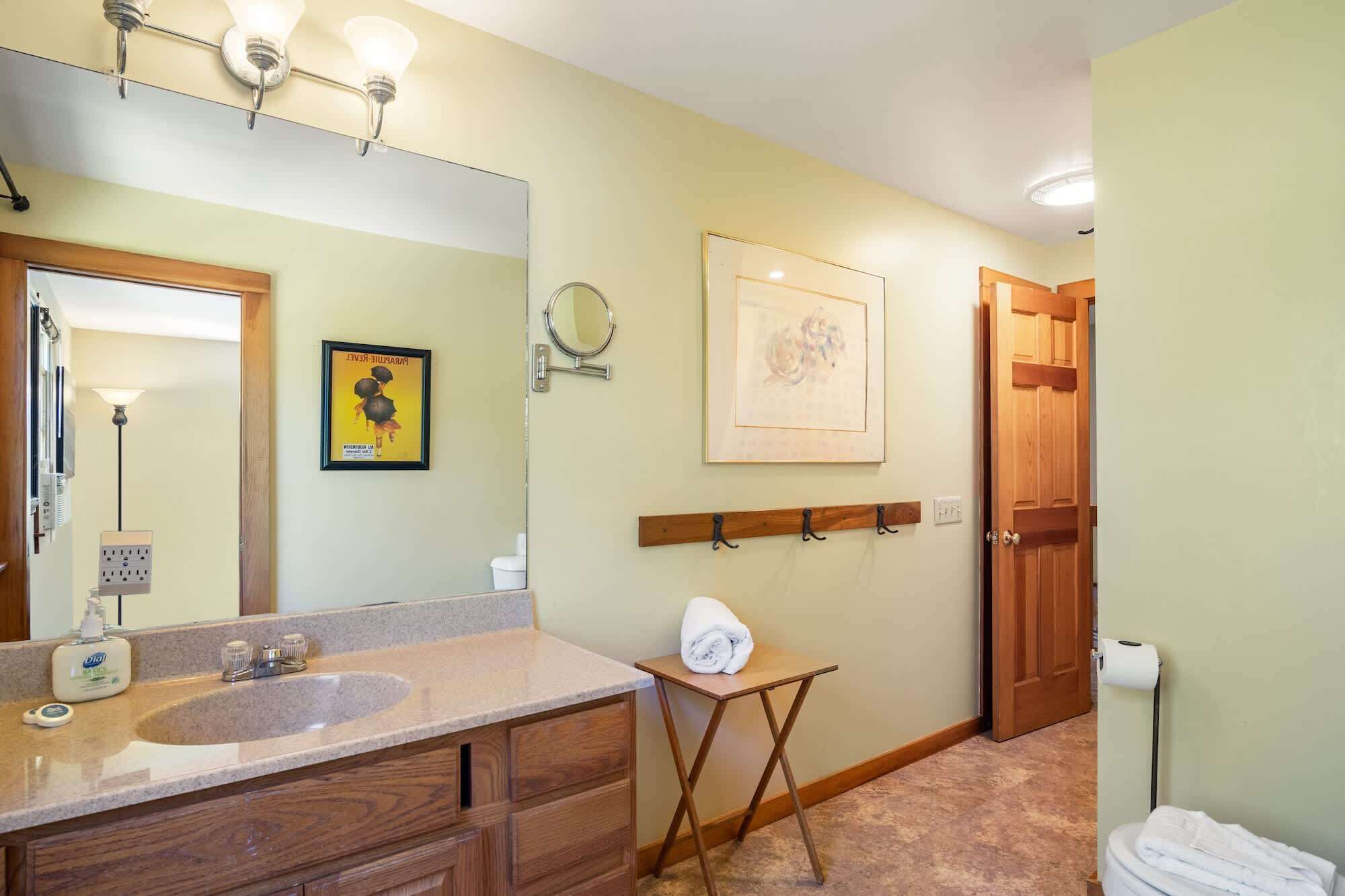 A bathroom with a sink, mirror, towel rack, and a door.