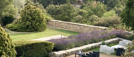 A landscaped garden with a stone wall, seating area, and a view of the surrounding countryside.