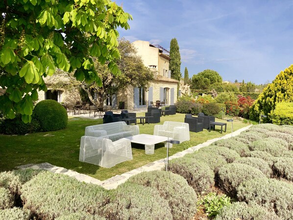 A garden with outdoor seating, stone buildings, and well-maintained hedges. - Domaine de l'Enclos (Gordes)