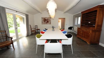 Ein Esszimmer mit einem langen Tisch, weißen Stühlen, einer Kristallleuchter und einem Holzkabinett.