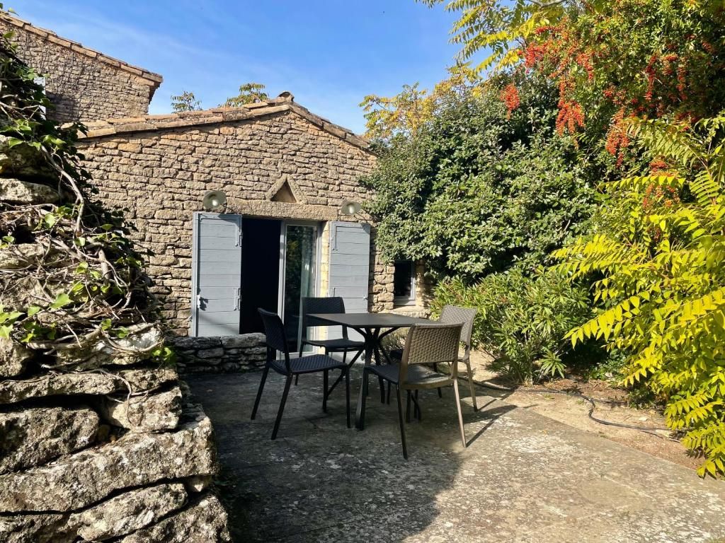 A stone building with a door, a table with chairs, and a garden with various plants.