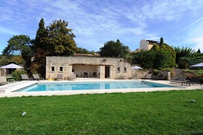 A stone building with a pool, surrounded by grass and trees. - Domaine de l'Enclos (Gordes)