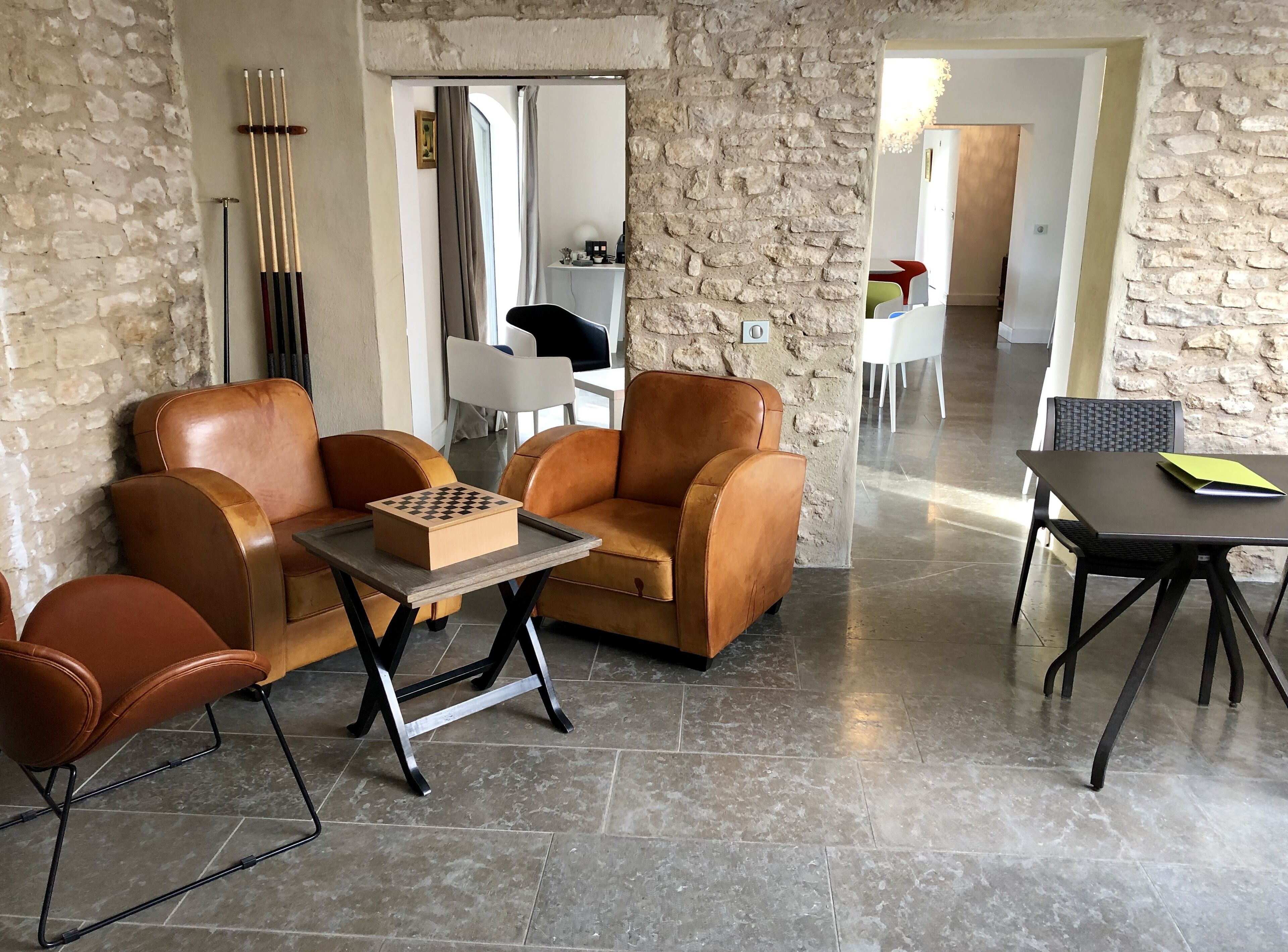 A living room with leather sofas, a chessboard, and a table with a laptop.