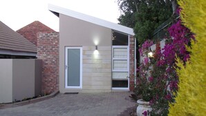 A modern house with a brick facade, a large glass door, and a small porch area. - The Suit Park @ Pentagon (Bloemfontein)