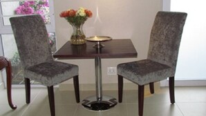 A dining table with two chairs, a vase with flowers, and a small plate on the table. - The Suit Park @ Pentagon (Bloemfontein)