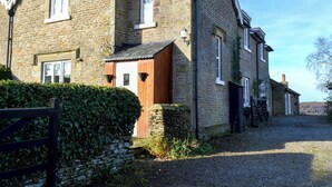 Une maison en pierre à l’architecture traditionnelle, dotée d’une porte en bois et d’une allée gravillonnée.