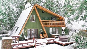 En stuga med en balkong, ett bubbelbad och en terrass med stolar.