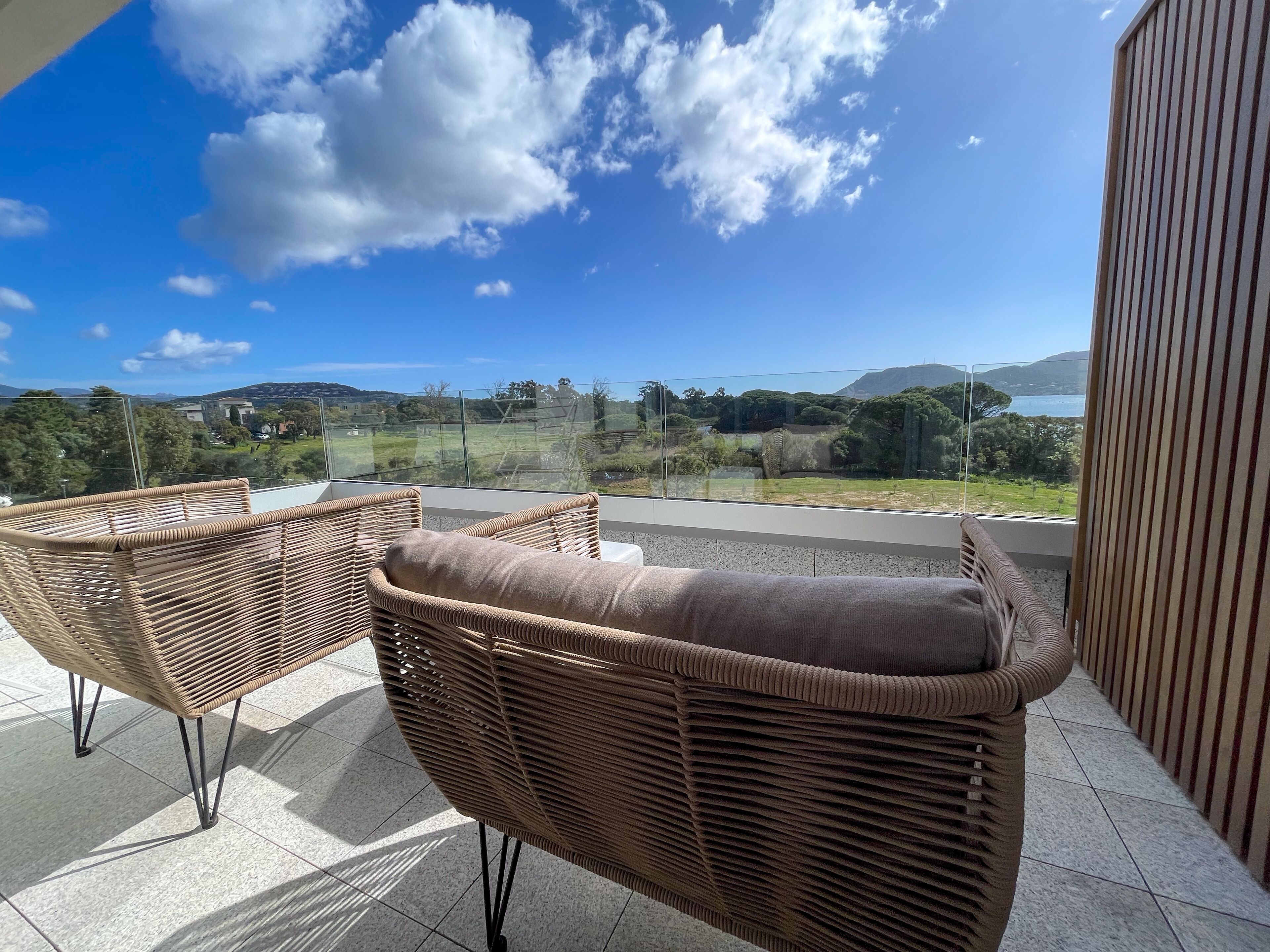 A balcony with wicker furniture and a clear view of the landscape.