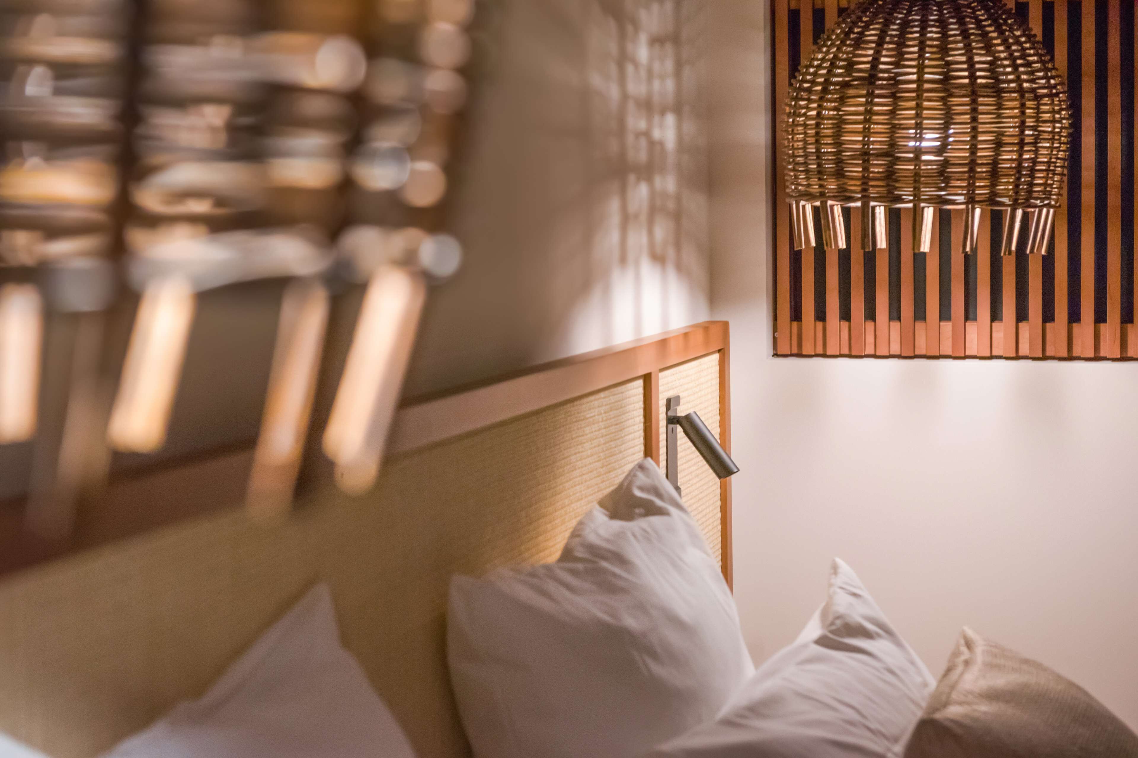 Una cama bien hecha con almohadas blancas y un cabecero de madera.