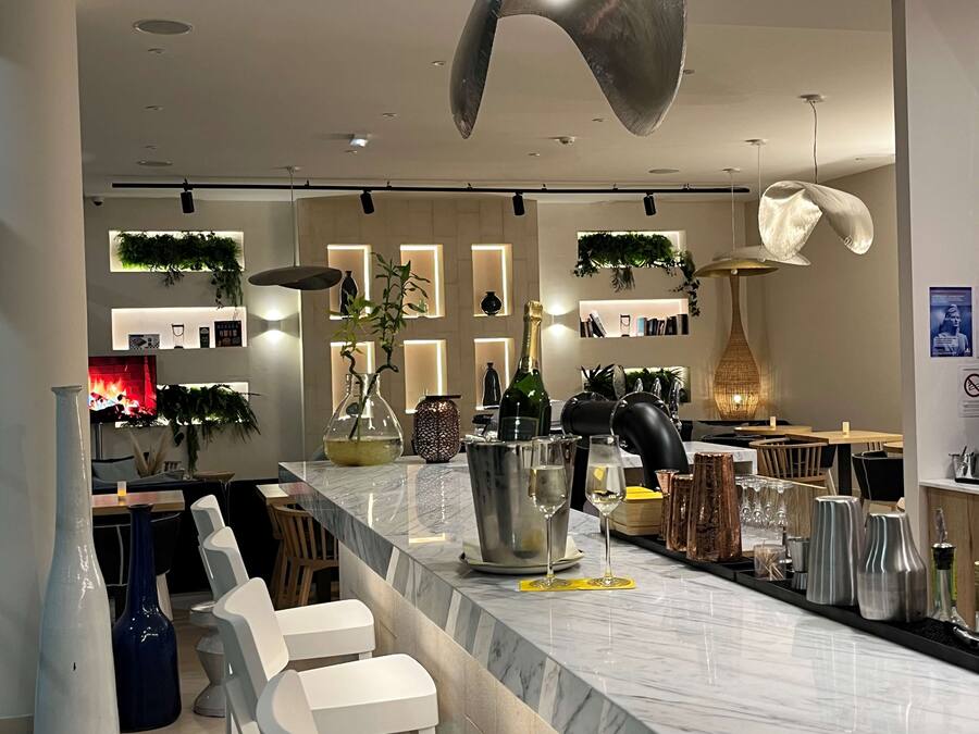 A modern bar area with marble countertops, white bar stools, and a variety of bar tools.