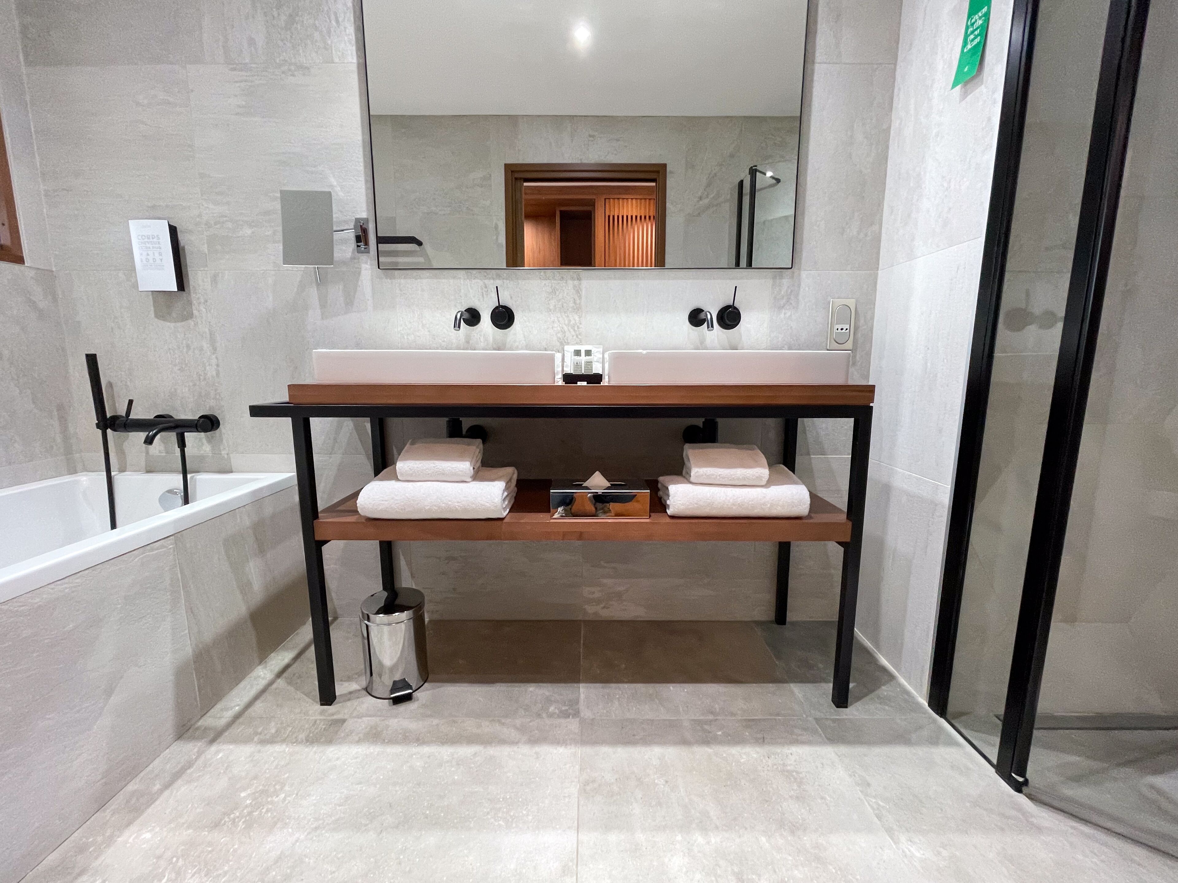 Un baño moderno con tocador doble lavamanos, un espejo grande y un box de ducha de vidrio.