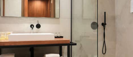 Un baño moderno con ducha de vidrio, tocador de madera y un espejo grande.