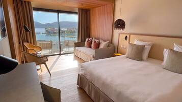 A hotel room with a large bed, a desk, a chair, and a view of a body of water.