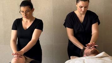 A massage therapy session in a room with tiled walls and a plain backdrop.
