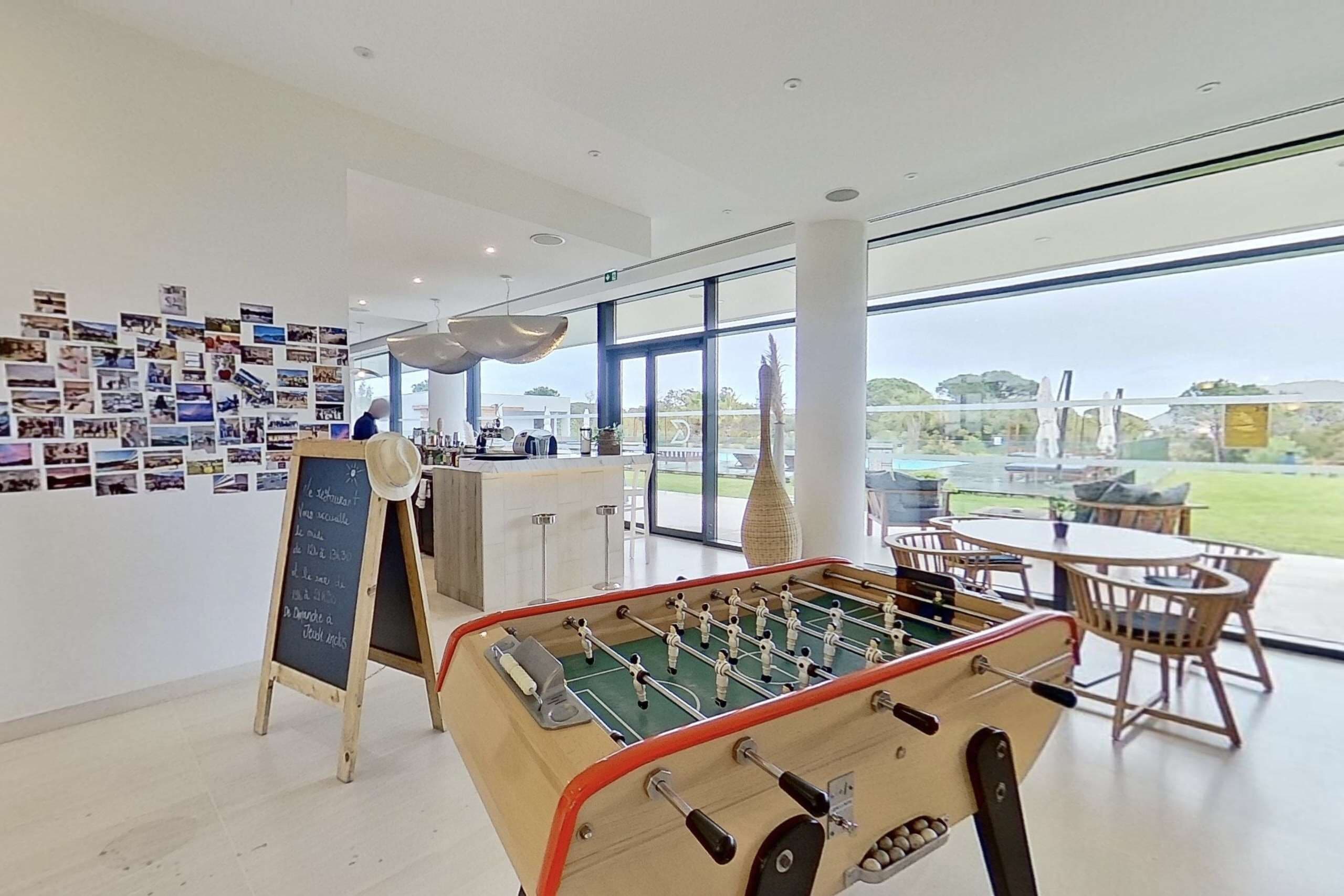 A modern indoor space with a foosball table, a wall of photographs, and a view of the outdoors.
