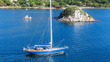Un voilier sur une étendue d’eau calme, avec une île rocheuse en arrière-plan.