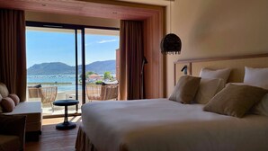A hotel room with a large bed, a desk, and a view of the sea.