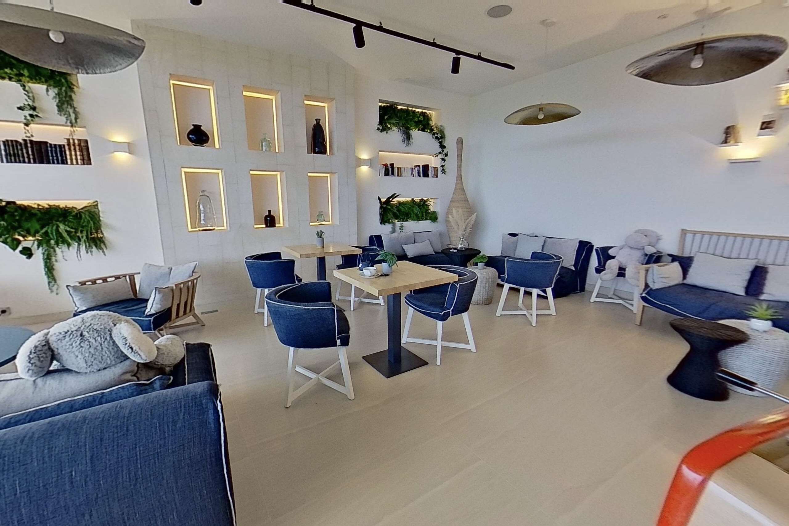 Um interior moderno com área de jantar, sofás e estante.