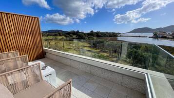 Un balcón con vistas a un lago, una pared de madera y un área de estar con mesa y sillas.