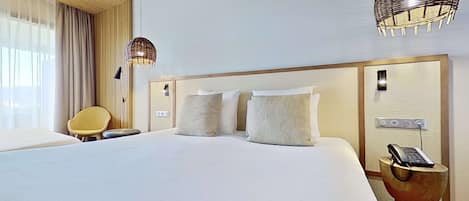 A hotel room with a large bed, two bedside lamps, a bedside phone, and a chair.