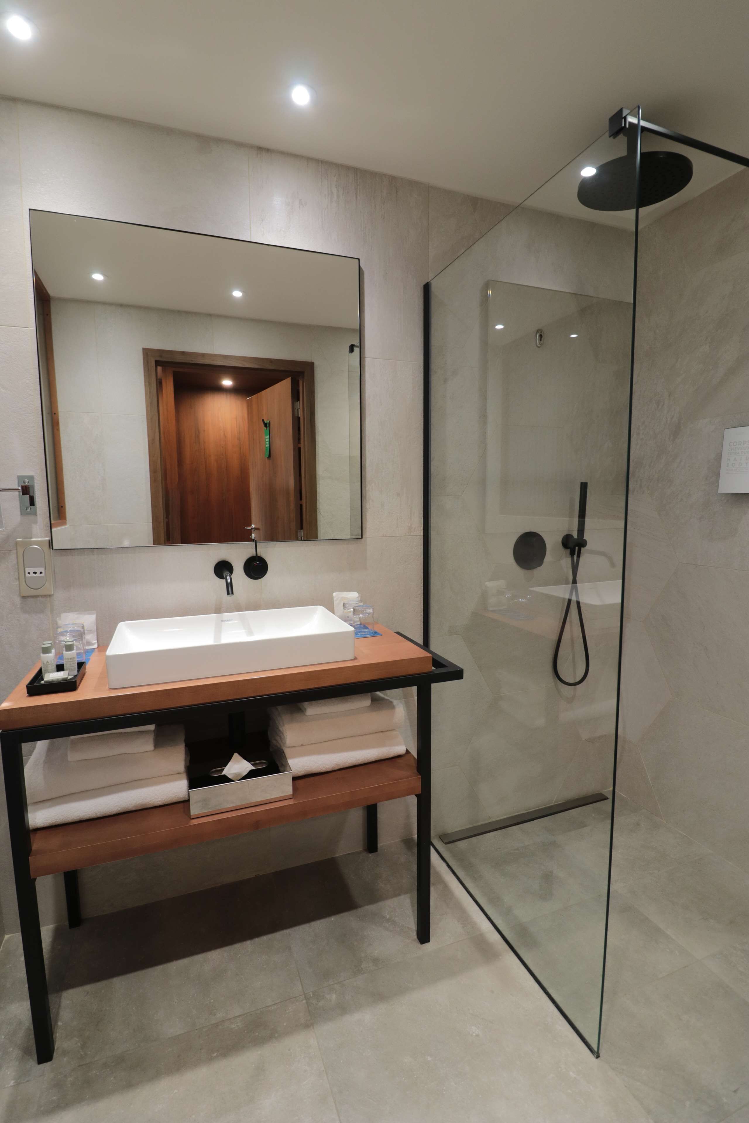Une salle de bain moderne avec un lavabo rectangulaire, un grand miroir et une douche à parois de verre.