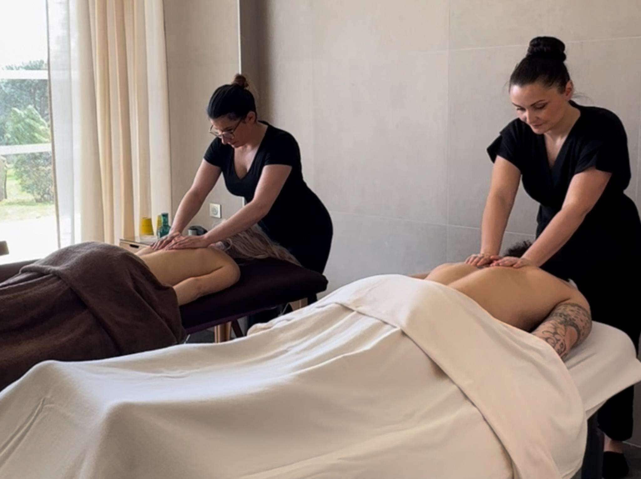 A massage therapy room with two clients receiving back massages.