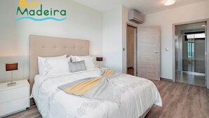 A modern bedroom with a large bed, a nightstand, a lamp, and a wardrobe.