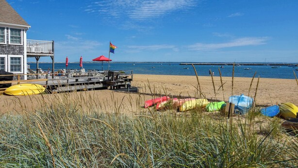 A beach with a wooden pier, beach umbrellas, and kayaks. - Beachfront with shared sundeck! (Provincetown)