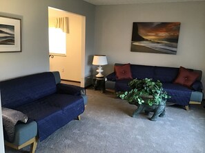 A living room with two sofas, a lamp, and a plant.