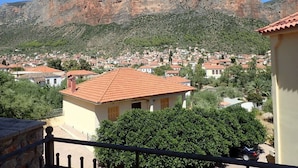 Um bairro residencial com telhados de telha vermelha, rodeado por colinas verdes e montanhas rochosas.