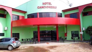 Hotelli nimeltä ”HOTEL CANCIONEIRO”, jonka julkisivu on punainen ja vihreä, ja jossa on ulkona oleva oleskelualue sekä auto parkissa sen edessä.