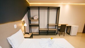 Hotellihuone, jossa on sänky, työpöytä, tuoli, vaatekaappi ja pieni keittonurkkaus.