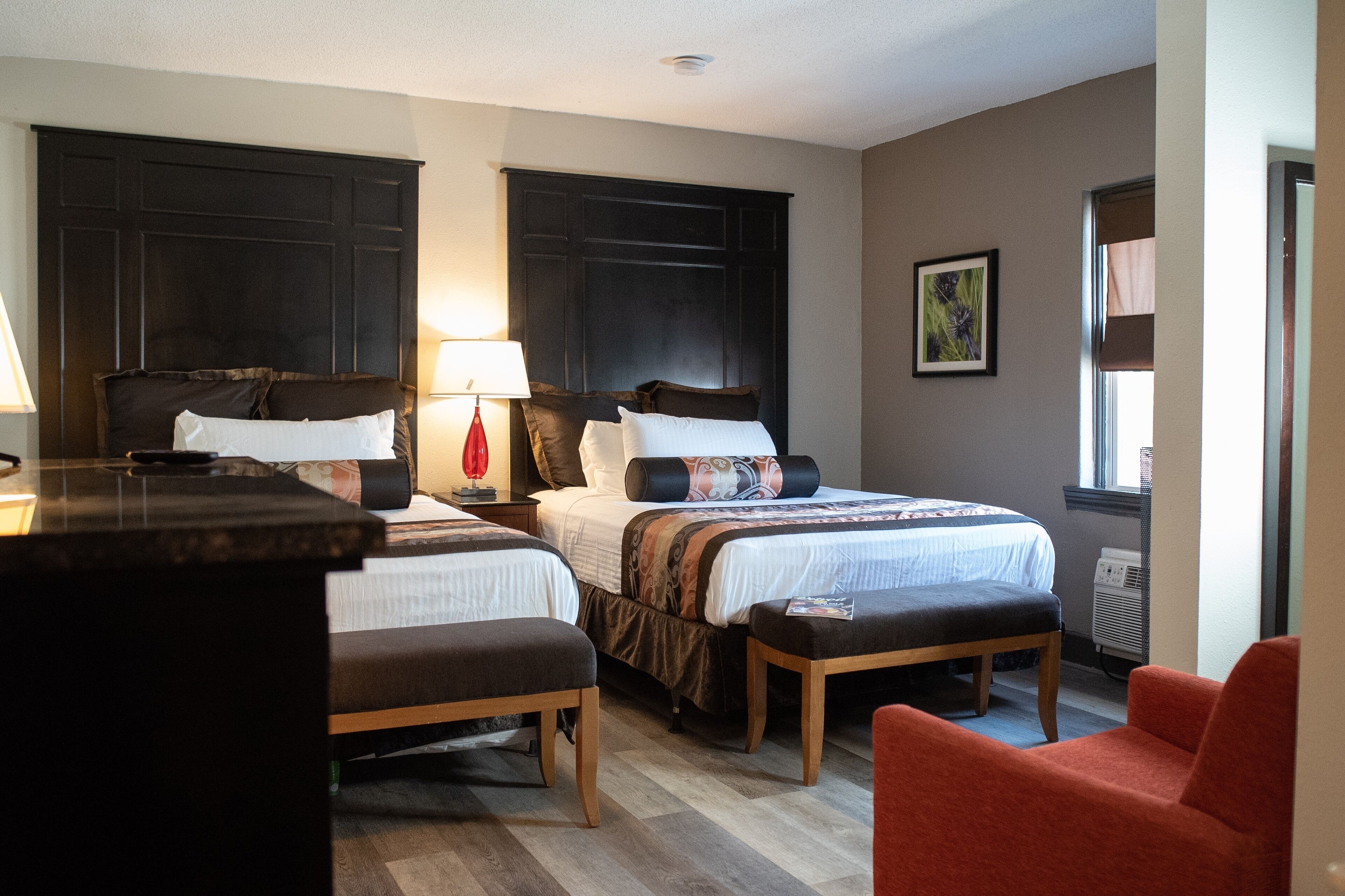 A hotel room with two beds, a desk, and a chair.