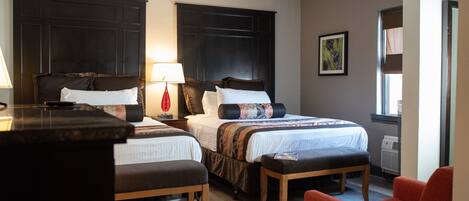 A hotel room with two beds, a desk, and a chair.
