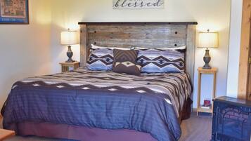 A bedroom with a bed, two bedside tables, a wall sign, and a lamp.