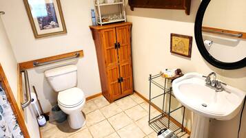A bathroom with a toilet, wooden cabinet, sink, and a mirror.