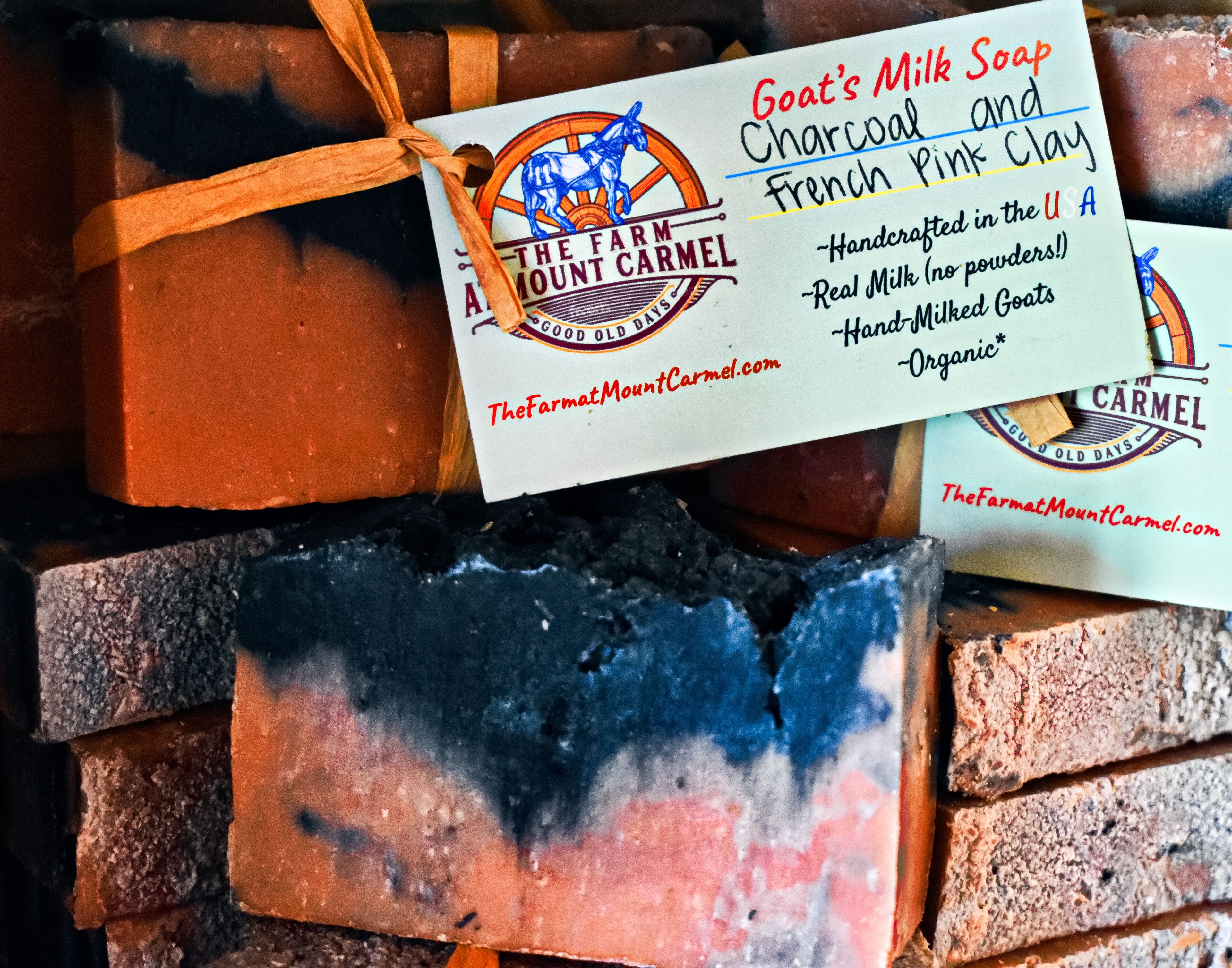 A soap bar with a tag that reads "Goat's Milk Soap Charcoal French Pink Clay" and mentions it's handcrafted in the USA.