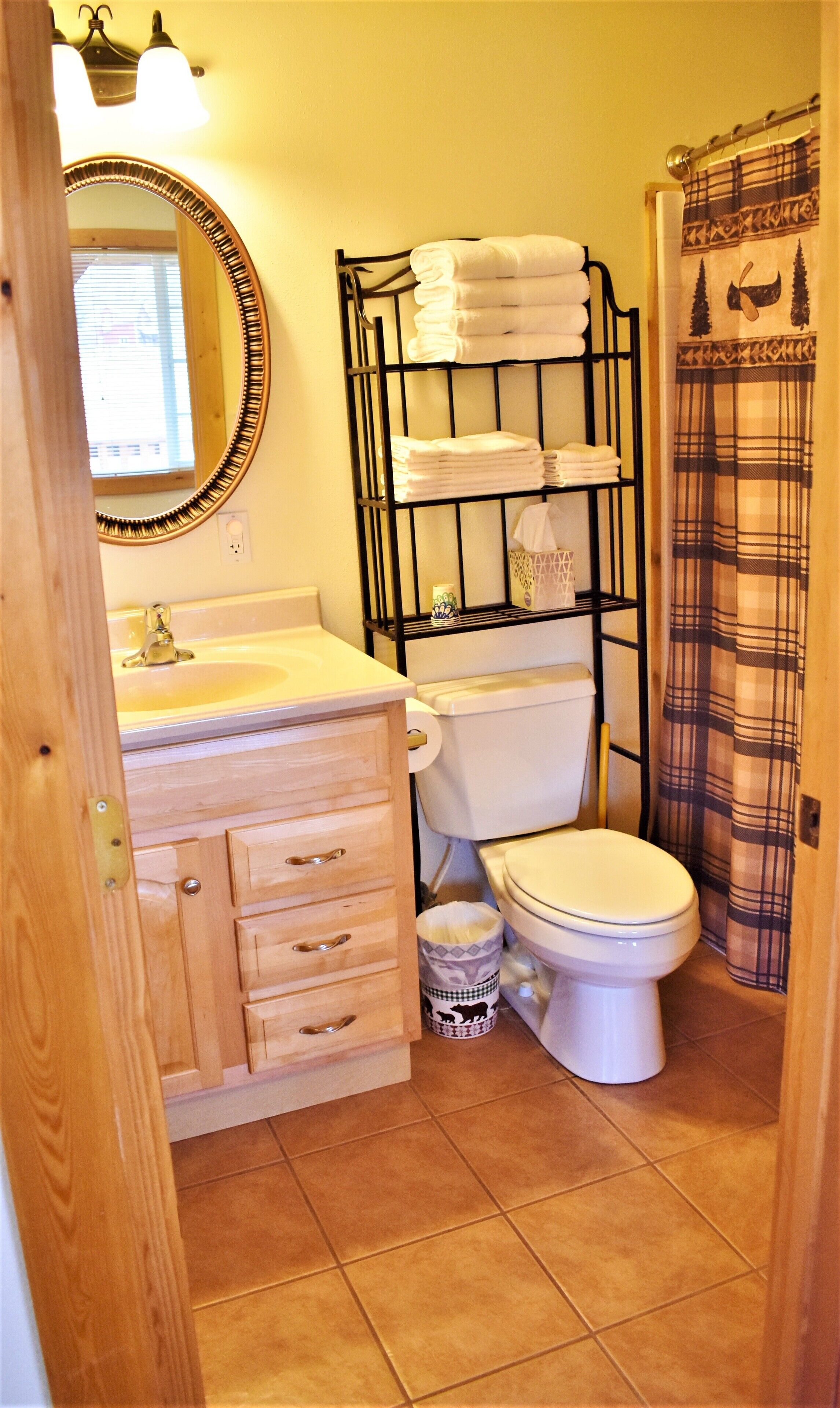 A bathroom with a toilet, sink, mirror, and a towel rack.