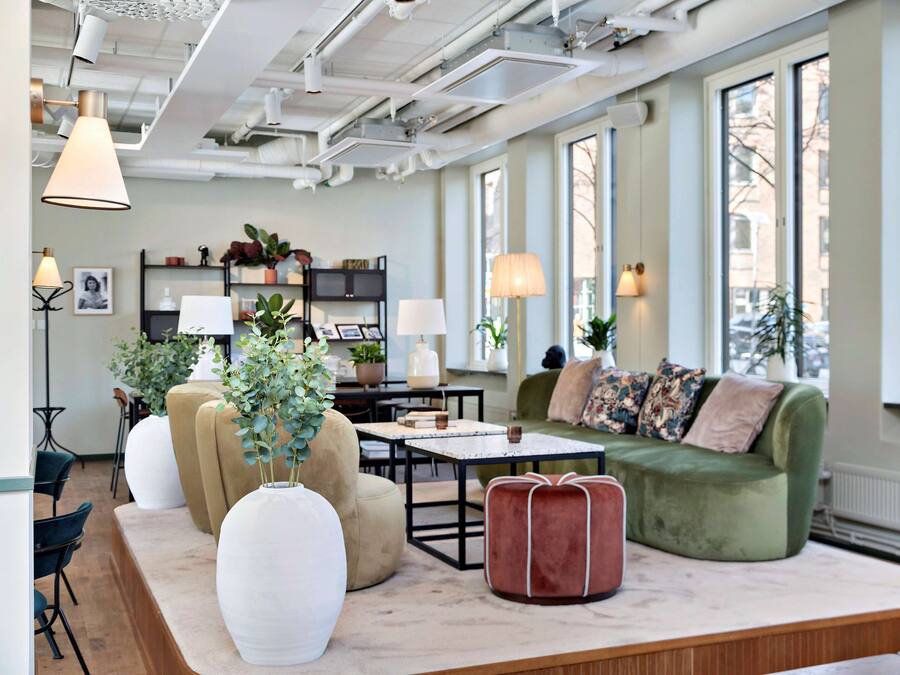 Een moderne woonkamer met een bank, stoelen, een salontafel en een boekenkast.
