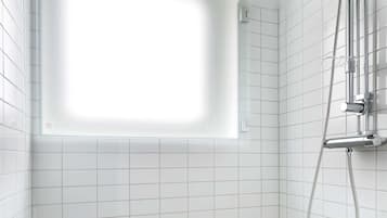 Un baño con paredes de azulejos blancos, una ducha con cabezal de ducha manual y un ventanal sobre la bañera.