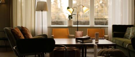A modern living room with a sofa, armchairs, a table, and a lamp.