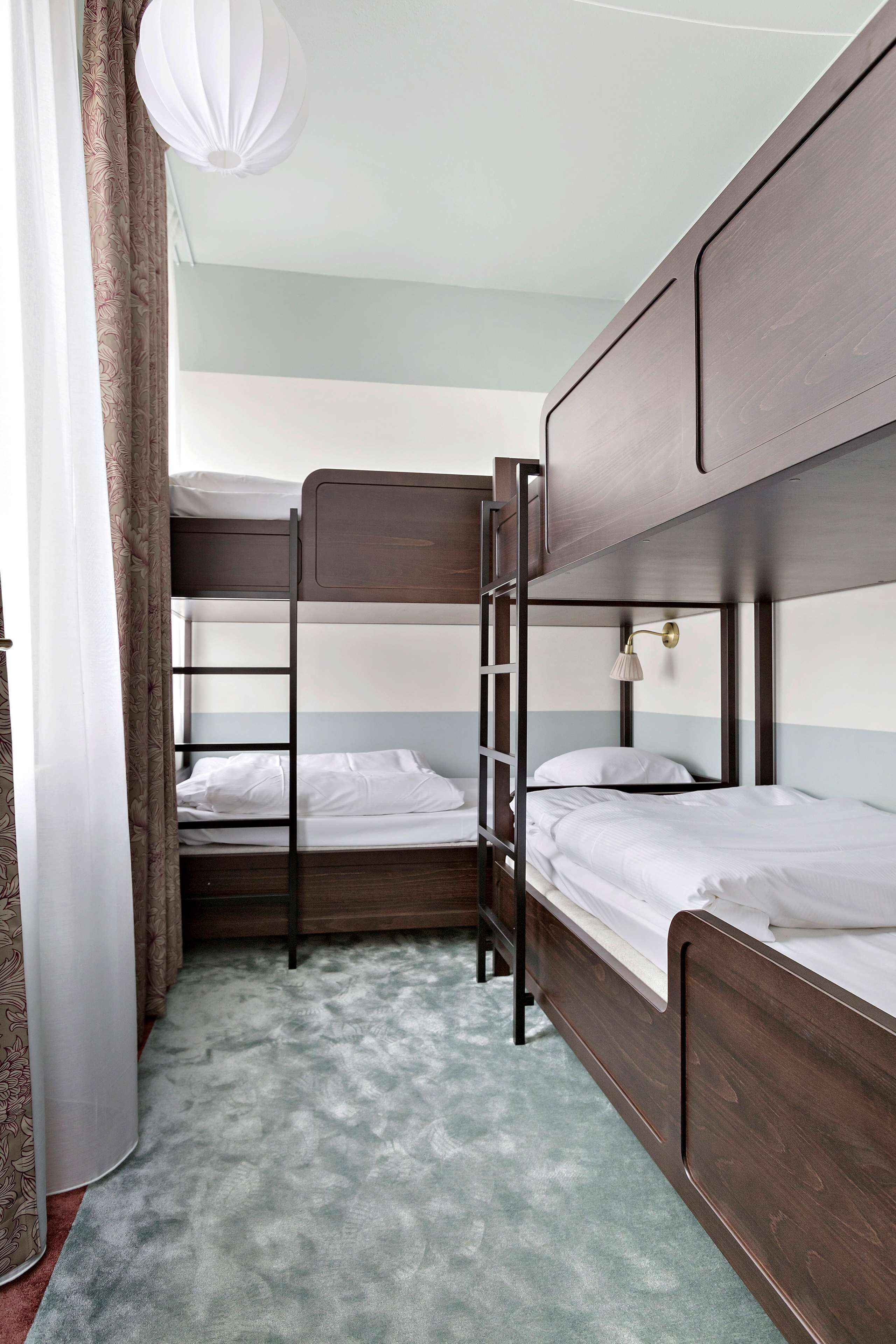 A bunk bed room with a ladder, a bedside table, and a hanging light fixture.