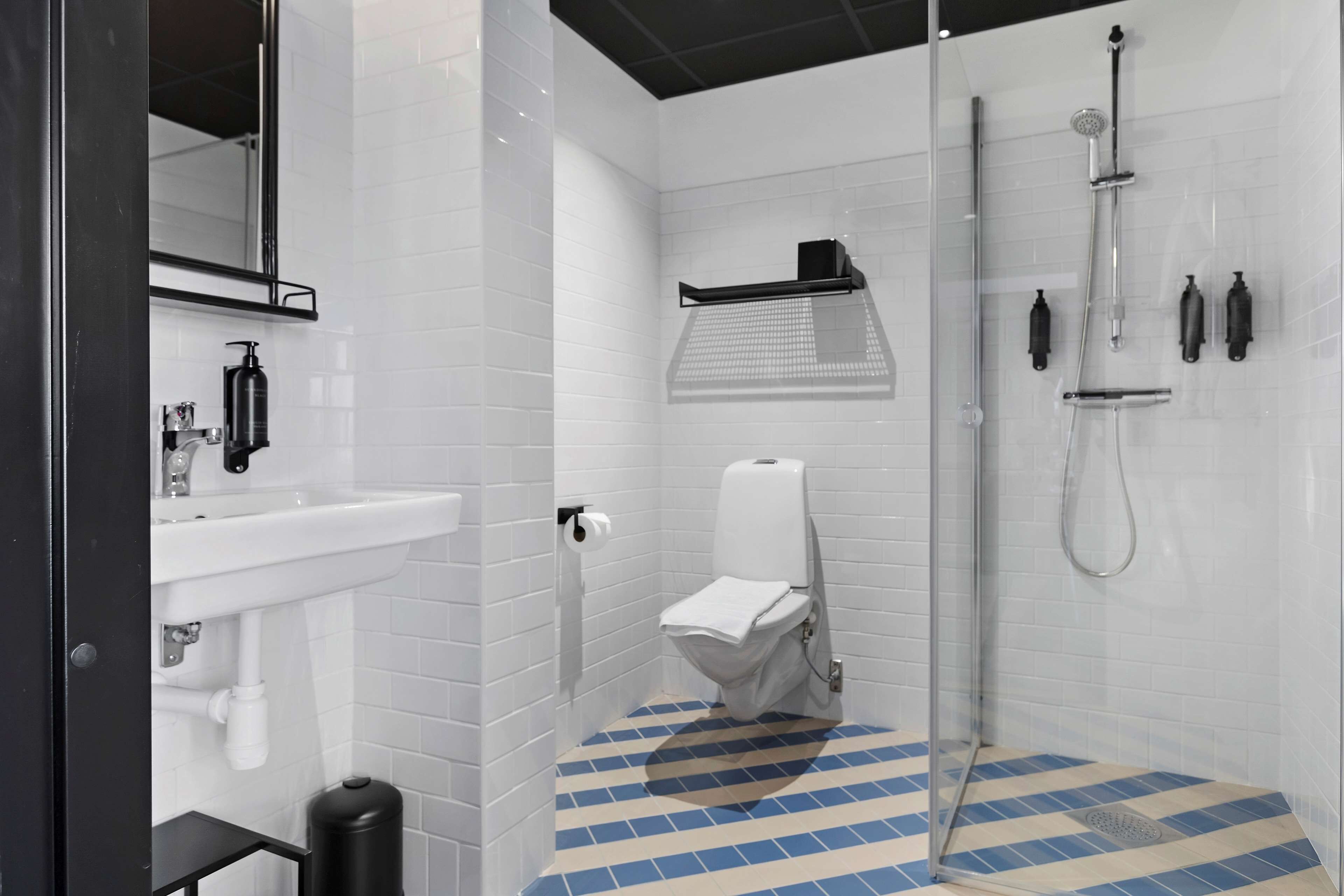 A modern bathroom with a white sink, toilet, and shower.