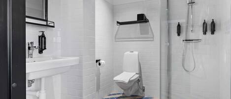 A modern bathroom with a white sink, toilet, and shower.