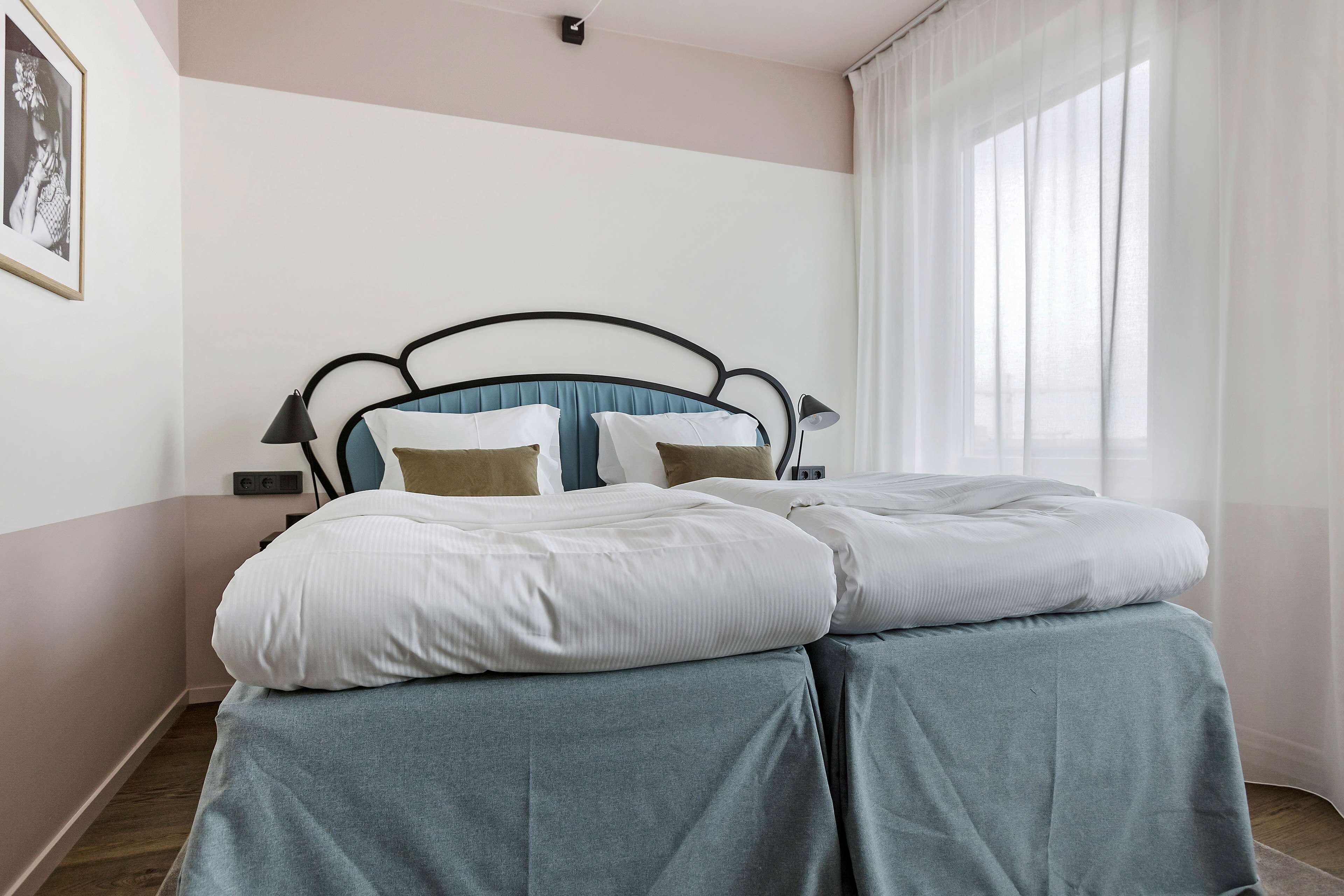Una cama bien hecha con un cabecero azul, ropa de cama blanca y falda azul claro.