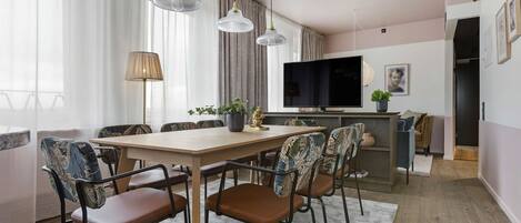 A modern dining area with a wooden table, brown chairs, and a large flat-screen TV.