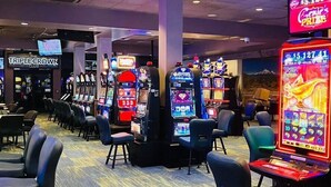 Un casino con numerosas máquinas tragamonedas, sillas y un letrero de neón anunciando un premio.