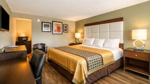 Una habitación de hotel con cama, escritorio, silla y televisor.