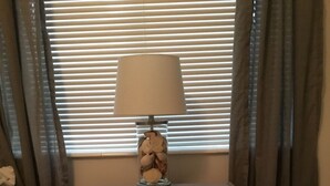 A bedroom with a nightstand, a lamp, a decorative item, and a sign on the nightstand.